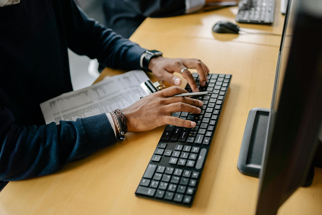 man typing on his keyboard while sitting at his desk