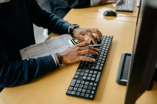 man typing on his keyboard while sitting at his desk