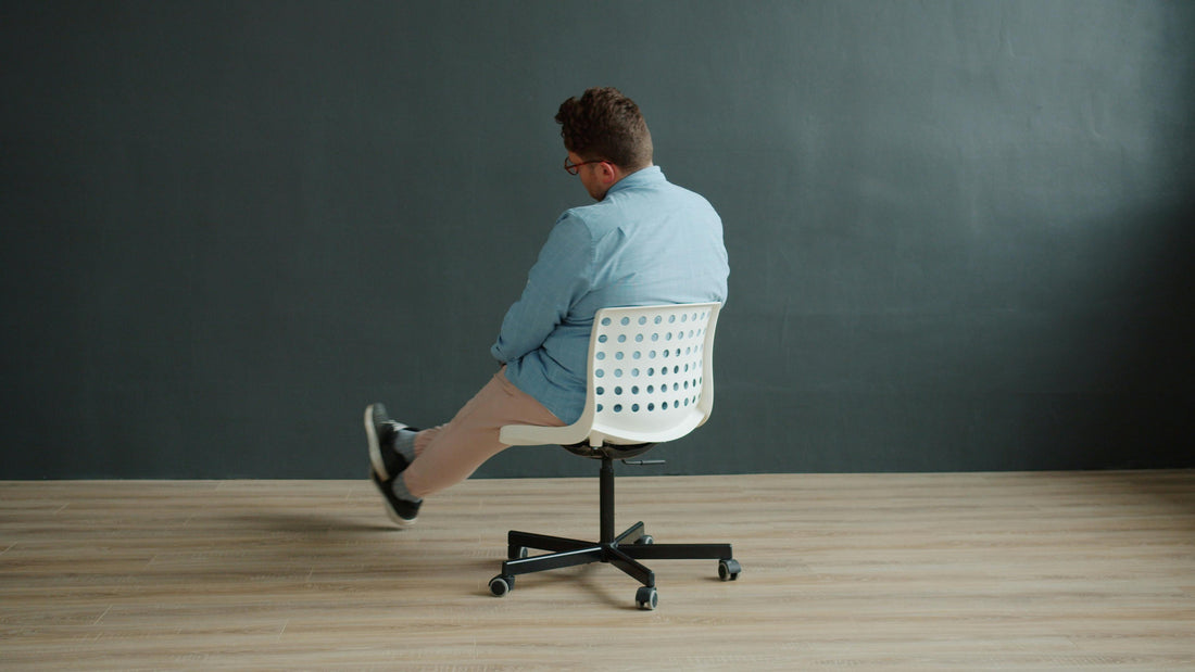 man sitting in a small, unsupportive rolling chair.