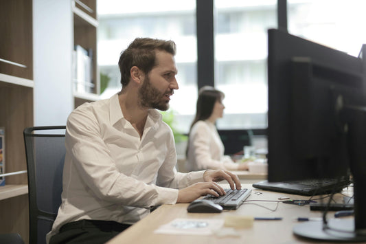 man in an office chair working on the computer wondering why good posture feels harder than it should.