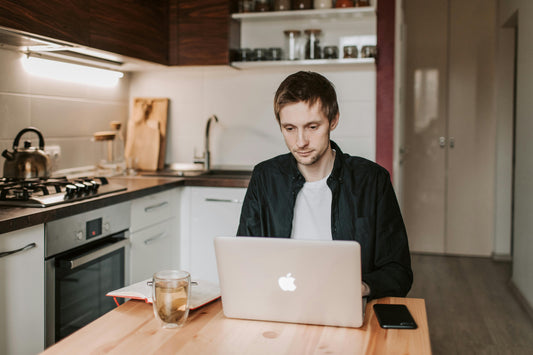 man working from home. sitting at his kitchen table working on his computer.